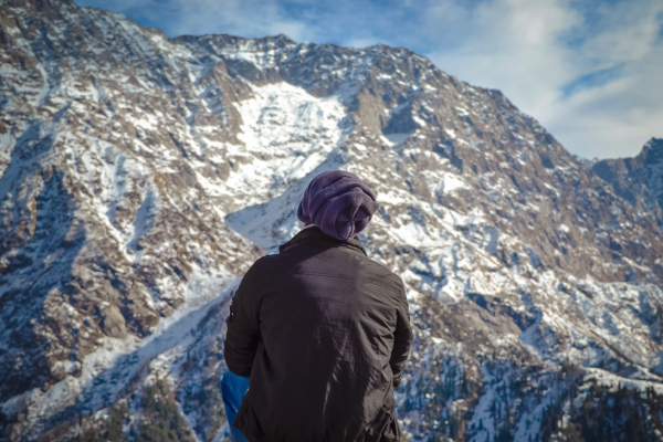 Person looking up to snow covered mountains