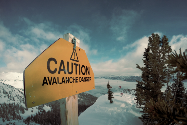 a sign that says caution avalanche danger with snowy background