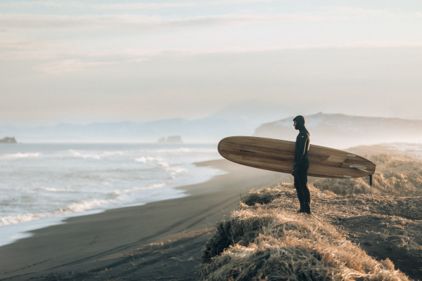 a surfer in a wetsuit looking at waves in foggy conditions