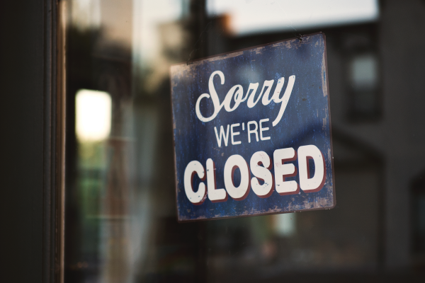 a sign hanging in a nondescript business window that says "sorry we're closed"