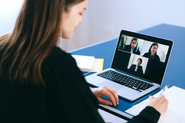 a person looking at their laptop displaying video conference with three people