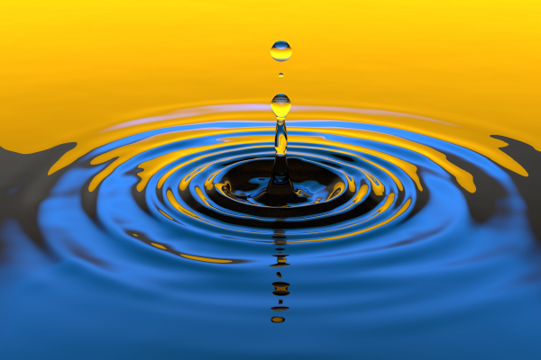 a droplet of water creating ripples in a reflection mixed with golden light
