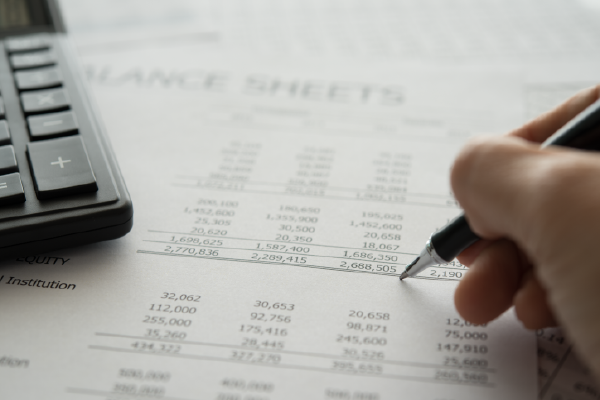 an image of balance sheets with a calculator on top