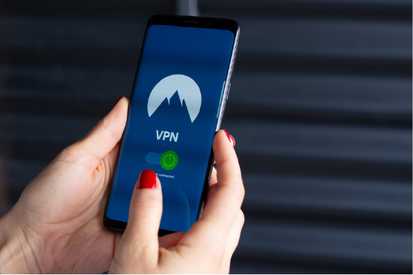 a person holding a phone with VPN app on the display, showing the letters "VPN" and and on-off slide button