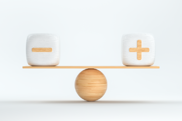 a wood plank balanced on a ball with a block on each end, one with a negative sign and one with a positive sign