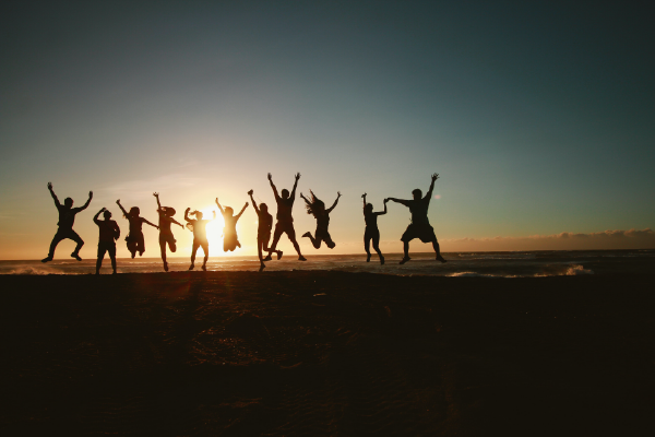 an image of the silhouettes of about ten people jumping with the sun directly behind them