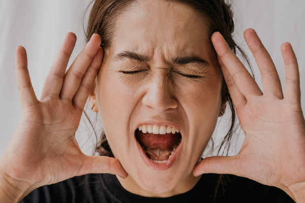 an image of a person with their hands on their face and mouth open, appearing angry