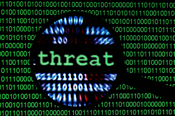 an image of the word threat in focus of a magnifying glass with binary code lines in the background