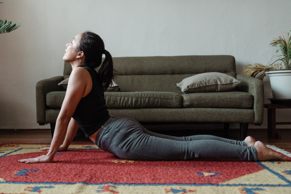 an image of a person in upward dog on a rug in front of a couch