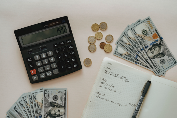 an image of an aerial desk view with money, a calculator, and notes