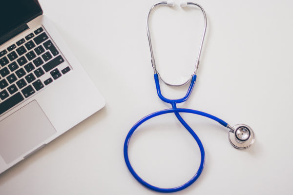 an image of a stethoscope on a desk next to a laptop
